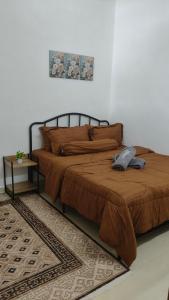 D'Raudhah Homestay : سرير في غرفة نوم مع لحاف بني