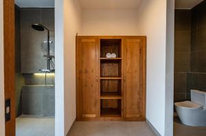 a bathroom with a toilet and a wooden door at KAPI Sebatu Villa in Tampaksiring +87 photos