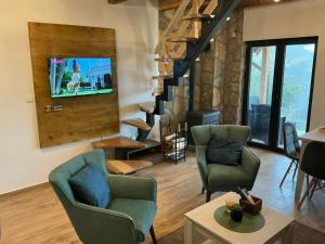 a living room with two chairs and a tv on a wall at Brvnara Šapat Borova Tara in Sekulić 