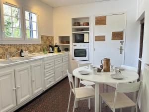 a kitchen with a white table and chairs and a sink at L'Oiselière - Campagne - Proche circuit - 5p in Mulsanne
