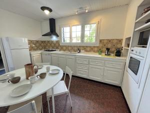 a kitchen with a white table and a white refrigerator at L'Oiselière - Campagne - Proche circuit - 5p in Mulsanne +7 photos