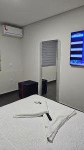 a white bed in a room with a tv on the wall at Lugar Aconchegante 3 in Palhoça