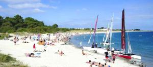 a crowd of people on a beach with sailboats at Location Maison Larmor plage in Larmor-Plage