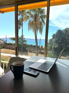 a laptop sitting on a table with a cup of coffee at Luxury Apartment with Sea View and Private Beach Access in Cannes