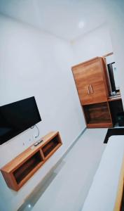 a living room with a tv and a wooden cabinet at Radission in Padinjarathara
