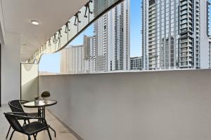 Una mesa y una silla en un balcón con edificios altos. en Riviera Azure Gateway Superior- 10min to Burj Khalifa, Dubai Mall and Airport and 20min to Marina, en Dubái
