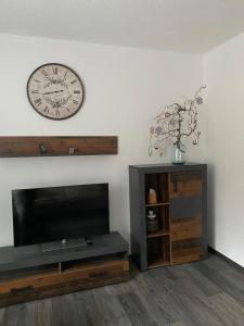 a living room with a tv and a clock on the wall at FEWO am Wald in Krauschwitz
