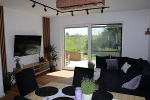 ŻelistrzewoLawendowe Zacisze的客厅里有一张黑色沙发和一台电视