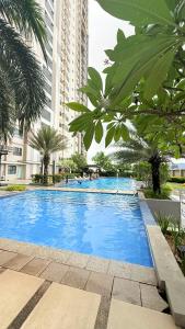 a large blue swimming pool with palm trees and buildings at LM50L2 horizon101 cebu in Cebu City