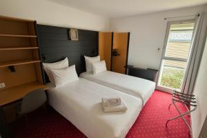 a hotel room with two beds and a window at Hôtel Restaurant Le Brennus in Langon