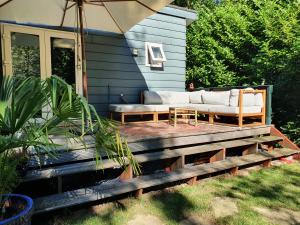 a patio with a couch and an umbrella on a house at Het Groene Hart in Groesbeek