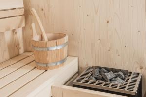 a sauna with a wooden bucket and some rocks at Aquila Dolomites Residence in Ortisei