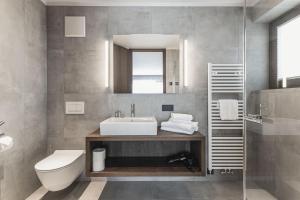 a bathroom with a sink and a toilet and a mirror at Aquila Dolomites Residence in Ortisei