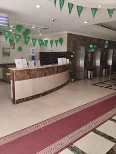 a lobby with a counter with green flags on the wall at فندق الخلفاء الفيصلية الفندقية in Mecca