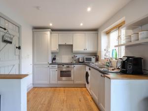 cocina con armarios blancos y suelo de madera en Riverview, en Somerford Keynes 24 fotos más