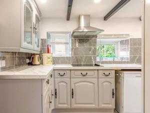 eine weiße Küche mit weißen Schränken und einer Spüle in der Unterkunft Sunnyside Cottage Retreat in Penwithick