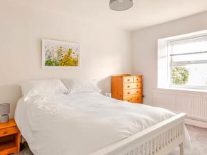 ein weißes Schlafzimmer mit einem weißen Bett und einem Fenster in der Unterkunft Sunnyside Cottage Retreat in Penwithick