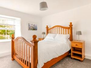 ein Schlafzimmer mit einem Holzbett und einem Fenster in der Unterkunft Sunnyside Cottage Retreat in Penwithick + 14 Fotos
