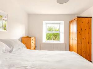 ein Schlafzimmer mit einem weißen Bett und einem Fenster in der Unterkunft Sunnyside Cottage Retreat in Penwithick