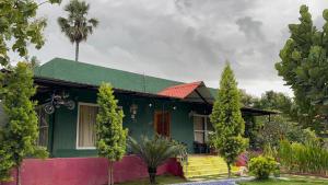a green house with a green roof and a palm tree at SR Farm Stay in Turkapally