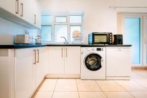 a kitchen with a washing machine and a microwave at Stay at a Minimalist Studio in Feltham with Parking in New Bedfont