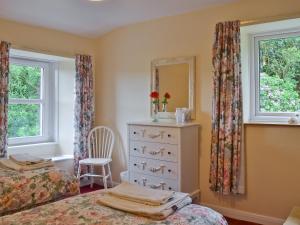 a bedroom with two beds and a dresser and a mirror at Bellegrove Cottage in Watermillock +10 photos
