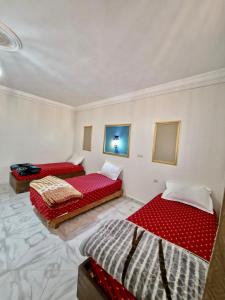 Oulad AkkouにあるResidence Hamada Laayoune - Family & Traveler Apartmentsの白い部屋のベッド2台 赤いシーツ付