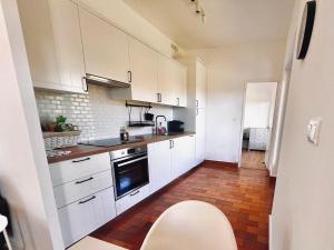 a kitchen with white cabinets and a red tile floor at Le Petit Bourdieu - Chouette in Jurançon