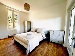 a bedroom with a bed and a dresser and two windows at Le Petit Bourdieu - Chouette in Jurançon