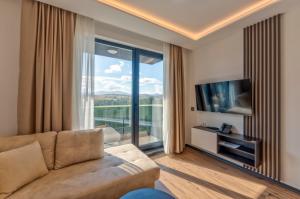 a living room with a couch and a large window at Villa Di Montagna wellness & spa in Zlatibor