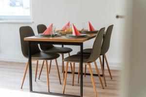 Una mesa de madera con sillas negras y tarjetas rojas sobre ella. en Zentrale Wohlfühlwohnung - Ideal für Ihren Urlaub oder die Geschäftsreise, en Magdeburgo