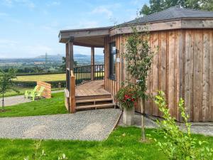 a wooden cabin with a deck in the grass at The Rabbit Hole - Uk50123 in Bodelwyddan