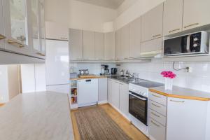 a white kitchen with white cabinets and white appliances at Big river view city apartment in Rovaniemi