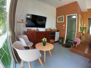 a living room with a table and chairs and a tv at ภูฝ้ายวิลล่า Phufai villa in Chiang Khan
