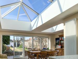 a conservatory with a glass roof with a table and chairs at Ron's House in Broadstairs