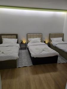 two twin beds in a room with two lamps at Neva's Hostel in Librazhd