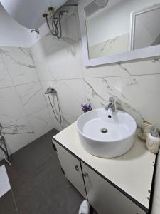a white bathroom with a sink and a mirror at Neva's Hostel in Librazhd