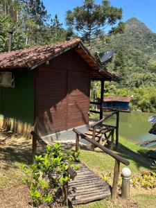 Una pequeña cabaña con un banco al lado de un cuerpo de agua. en Estação Serramar, en Lumiar