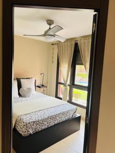 a bedroom with a bed with a ceiling fan and a window at Coqueto apartamento en ARona el PAlm-mar. in Arona
