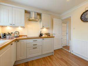 a kitchen with white cabinets and a clock on the wall at Seaglass House in Beadnell +20 photos