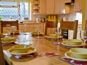 a wooden table with plates and glasses on it at Green Acre Cottage in Kilgetty