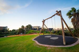 a playground in a park with a swing at Modern Studio Steps from Ratanga Park in Cape Town +2 photos