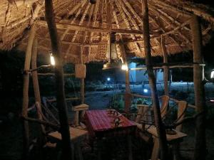 a tent with a table and chairs under a straw umbrella at Makucha Ya Simba Homestay and camping grounds in mwanza in Mwanza