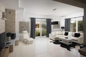 a living room with a white couch and a tv at Villa Piccolo Paradiso with Heated Pool, Jacuzzi & Sauna in Rovinjsko Selo