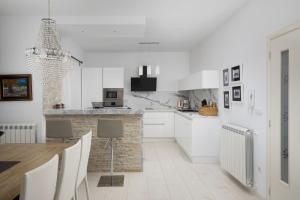 a kitchen with white cabinets and a table with chairs at Villa Piccolo Paradiso with Heated Pool, Jacuzzi & Sauna in Rovinjsko Selo
