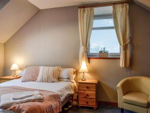 a bedroom with a bed and a window and a chair at Airdside Cottage in Crossmichael +6 photos