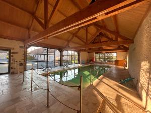 an indoor swimming pool with green water in a building at MAISON DE VACANCES AVEC PISCINE INTERIEURE - Le Grand Champagne in Saint-Victeur