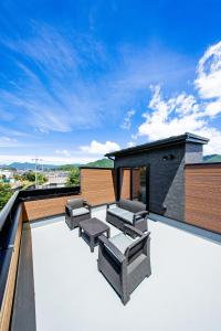 an outdoor patio with chairs and tables on a roof at Sky deck for rent! Fuji view Open-air bath New building in Fujiyoshida
