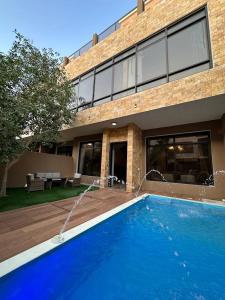 una casa con una piscina azul frente a un edificio en فلل بكمباوند خاص, en Riad