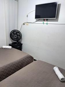 a bedroom with two beds and a flat screen tv on the wall at Rincón del Café - a 4 minutos del Parque del Café 321-435-21-00 in Montenegro +16 photos